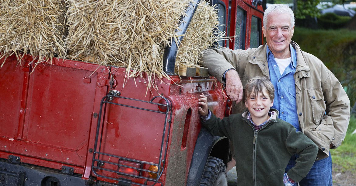 Grandfather and grandson standing next to truck of hay