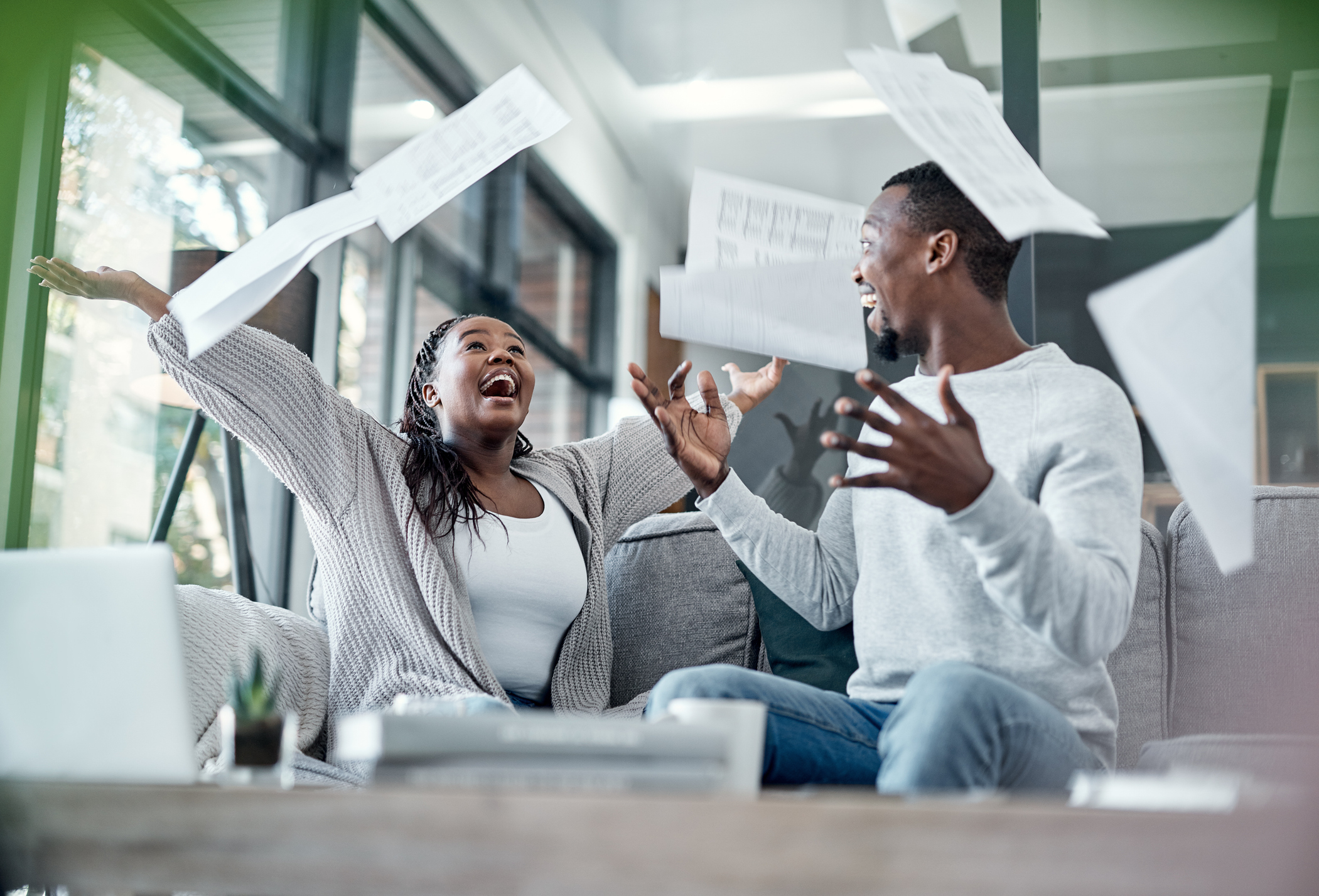 young couple tossing paperwork in the air as they celebrate financial freedom