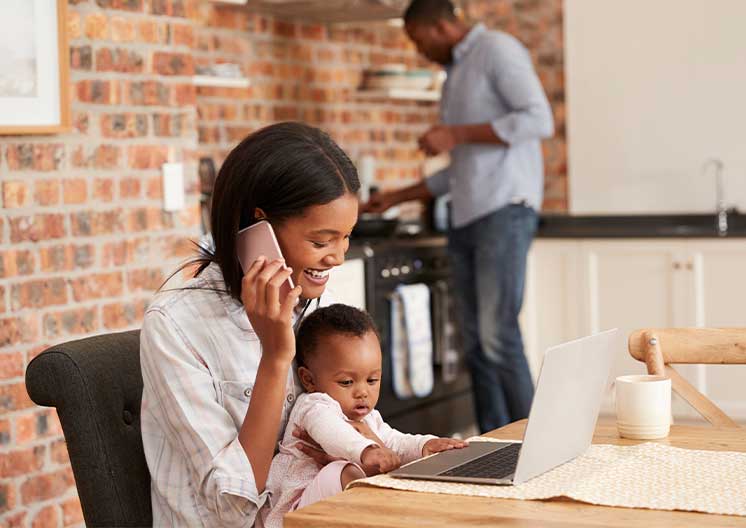 Mother holding child while paying personal loan online.